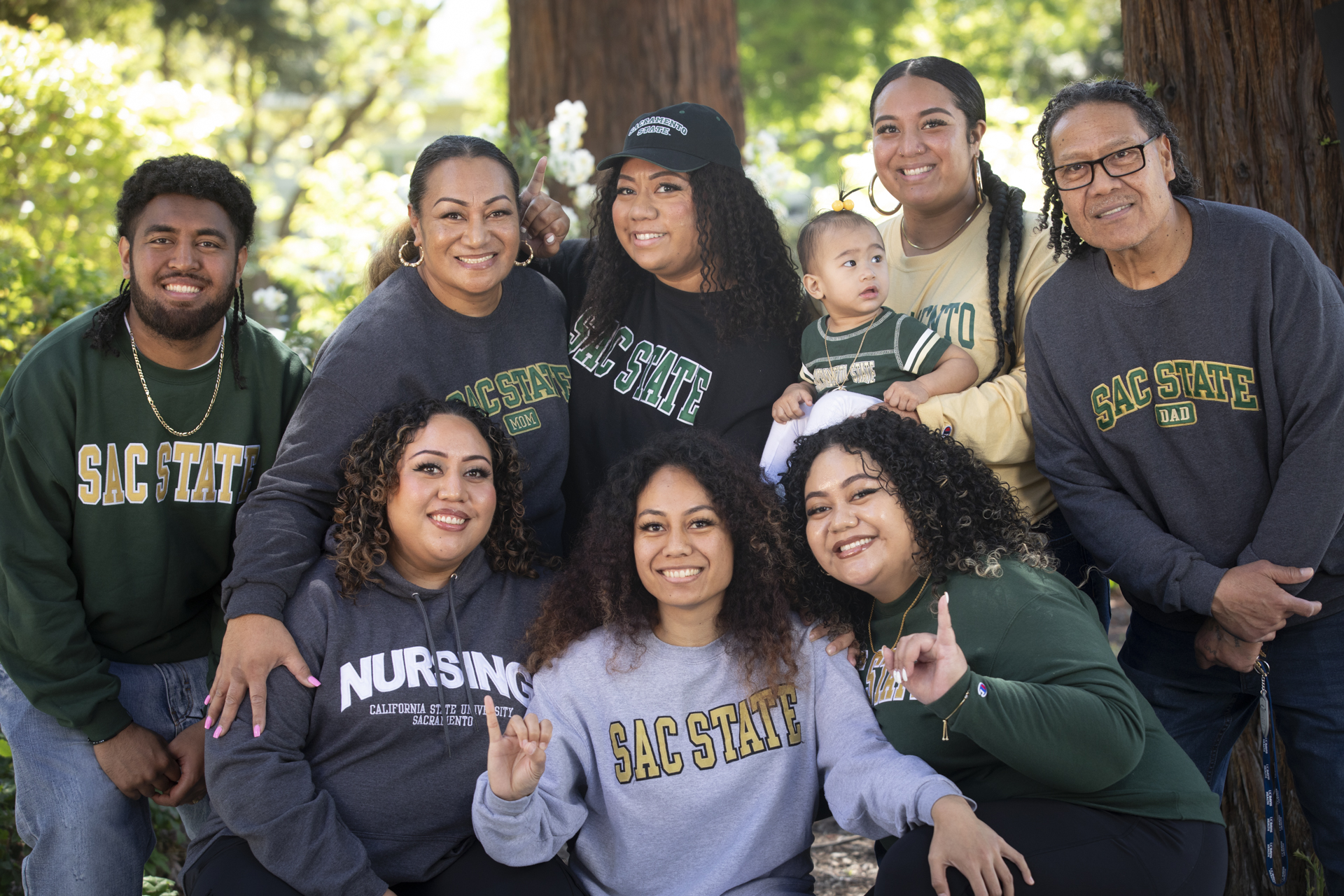 The six Koloamatangi siblings, their parents and a baby, all wearing Sac State gear, pose for a photo.