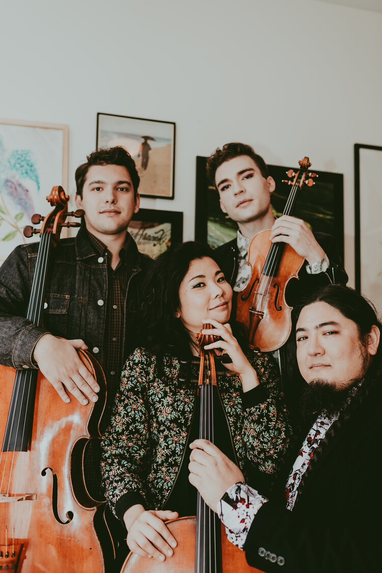 image of Owls Quartet members with string instruments in front of a wall of framed art