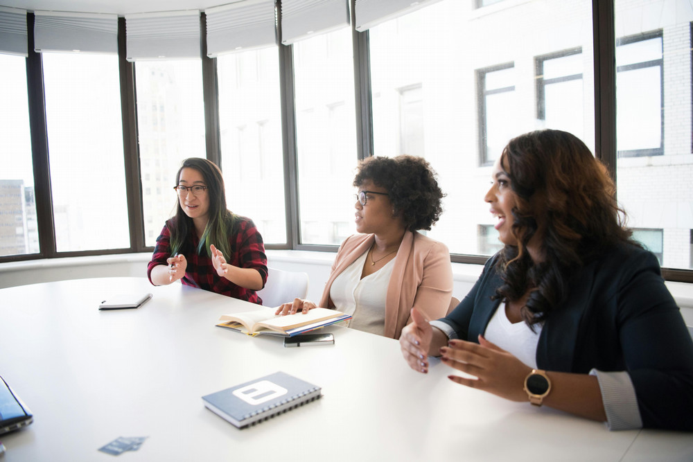 three people communicating at table