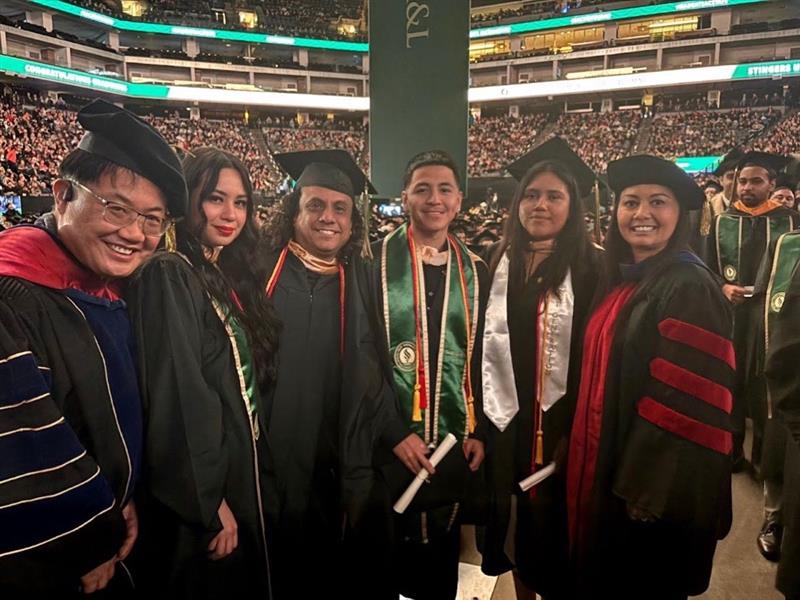 two faculty of Spanish with four graduates at their commencement ceremony