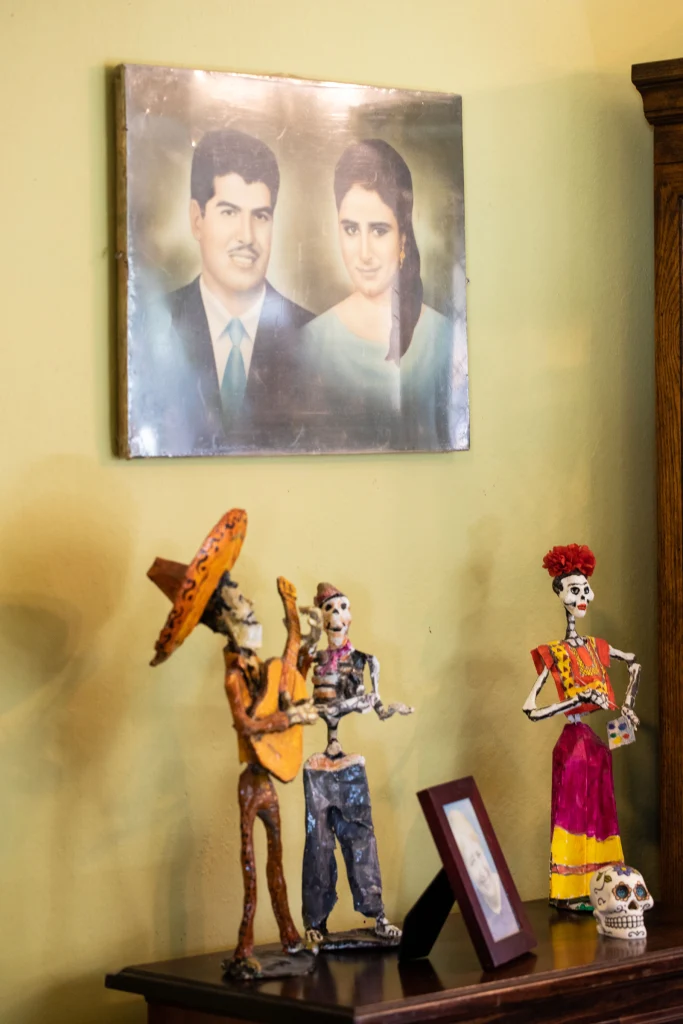 A portrait of Henry and Catalina Barela on the wall, above traditional Mexican figurines and a photo of Catalina.