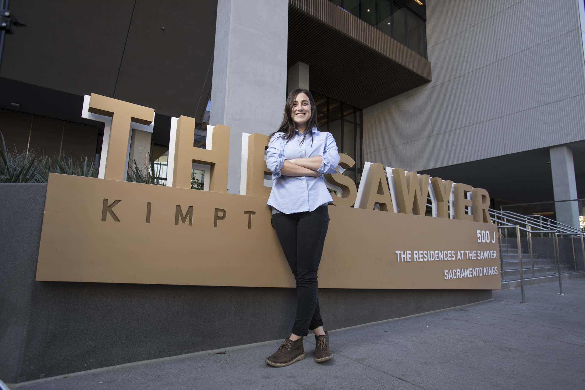 Alyssa Zayas standing in front of a sign reading "The Sawyer."