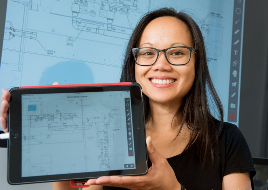 Tracy Young holding an iPad displaying the PlanGrid software.