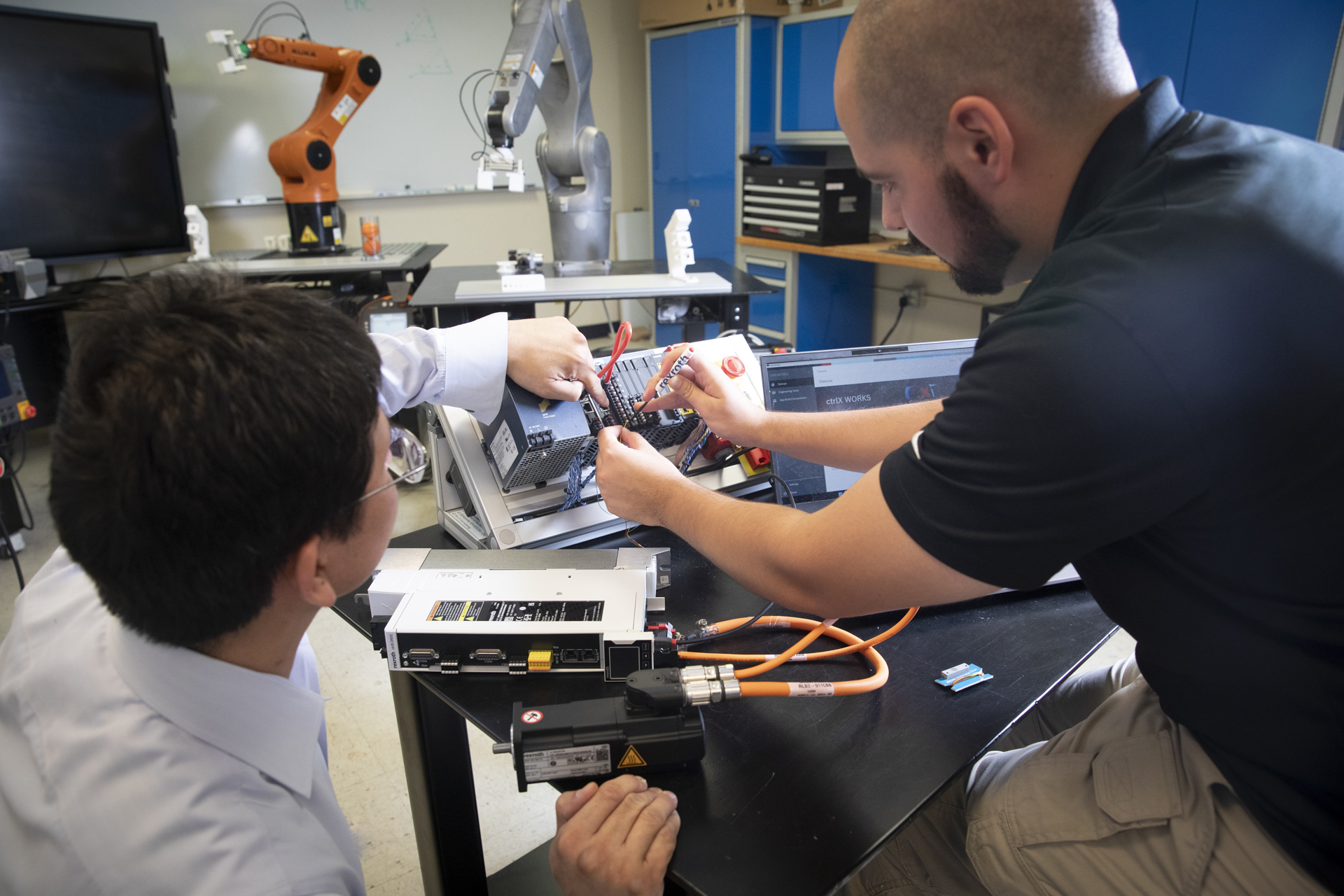 A student and professor work on robotics equpment.