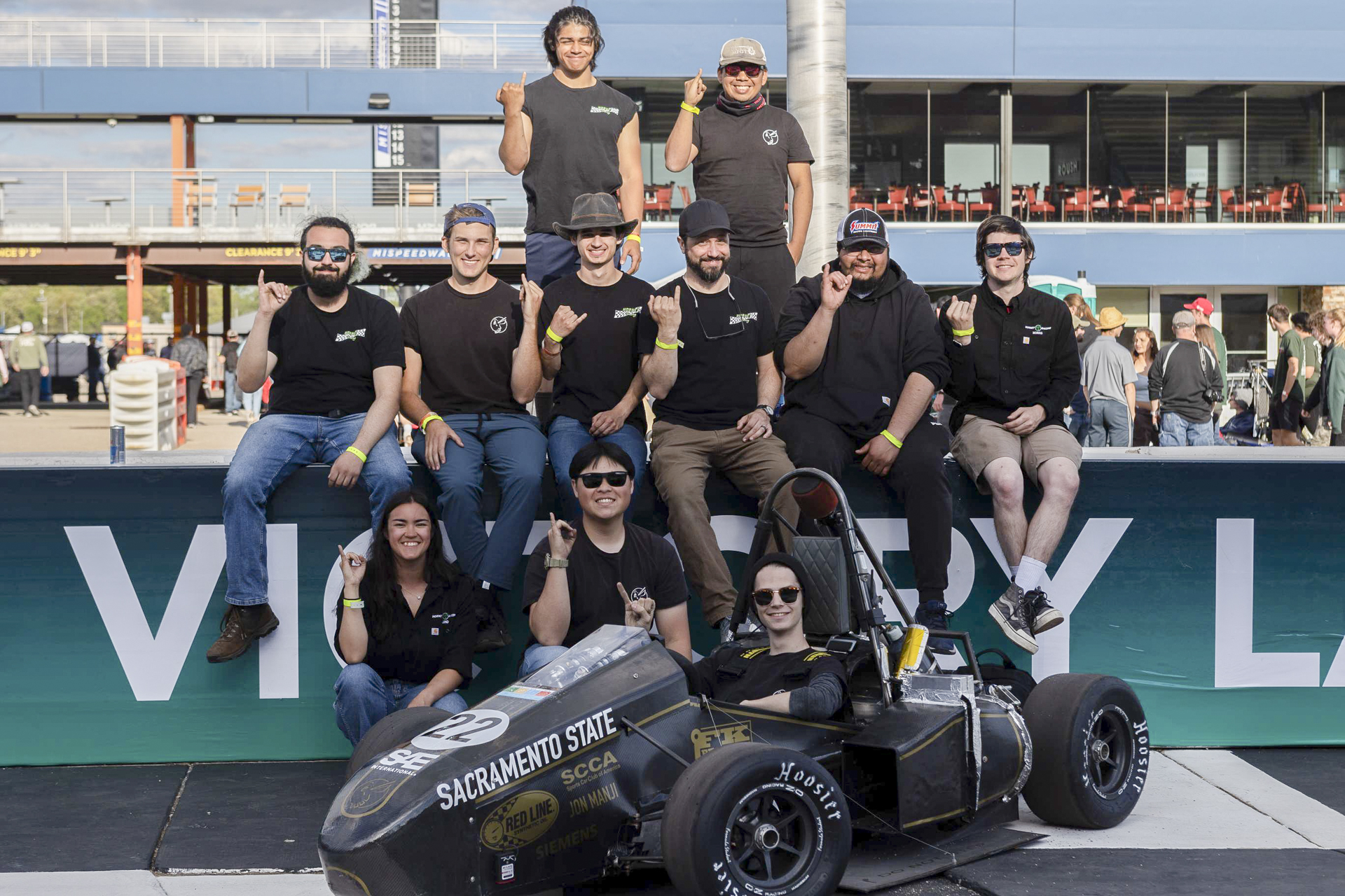 Members of the Sacramento State Hornet Racing team posing for a photo with their race car.