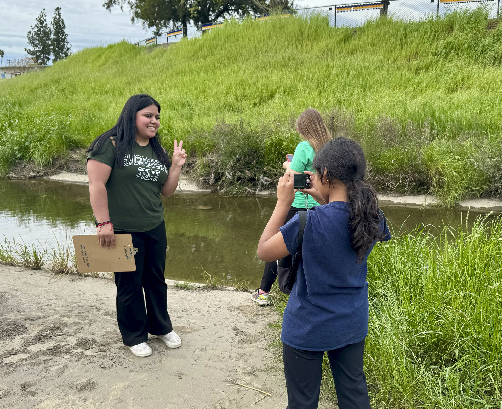A Sac State student and two elementary students take photos at Morrison Creek.