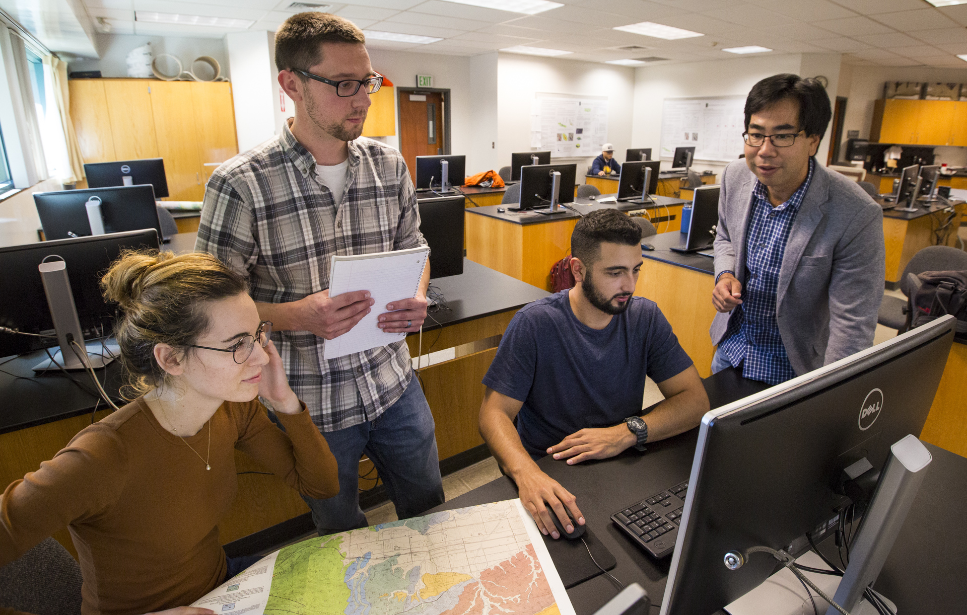 Student and faculty researchers work on a project at a computer. 