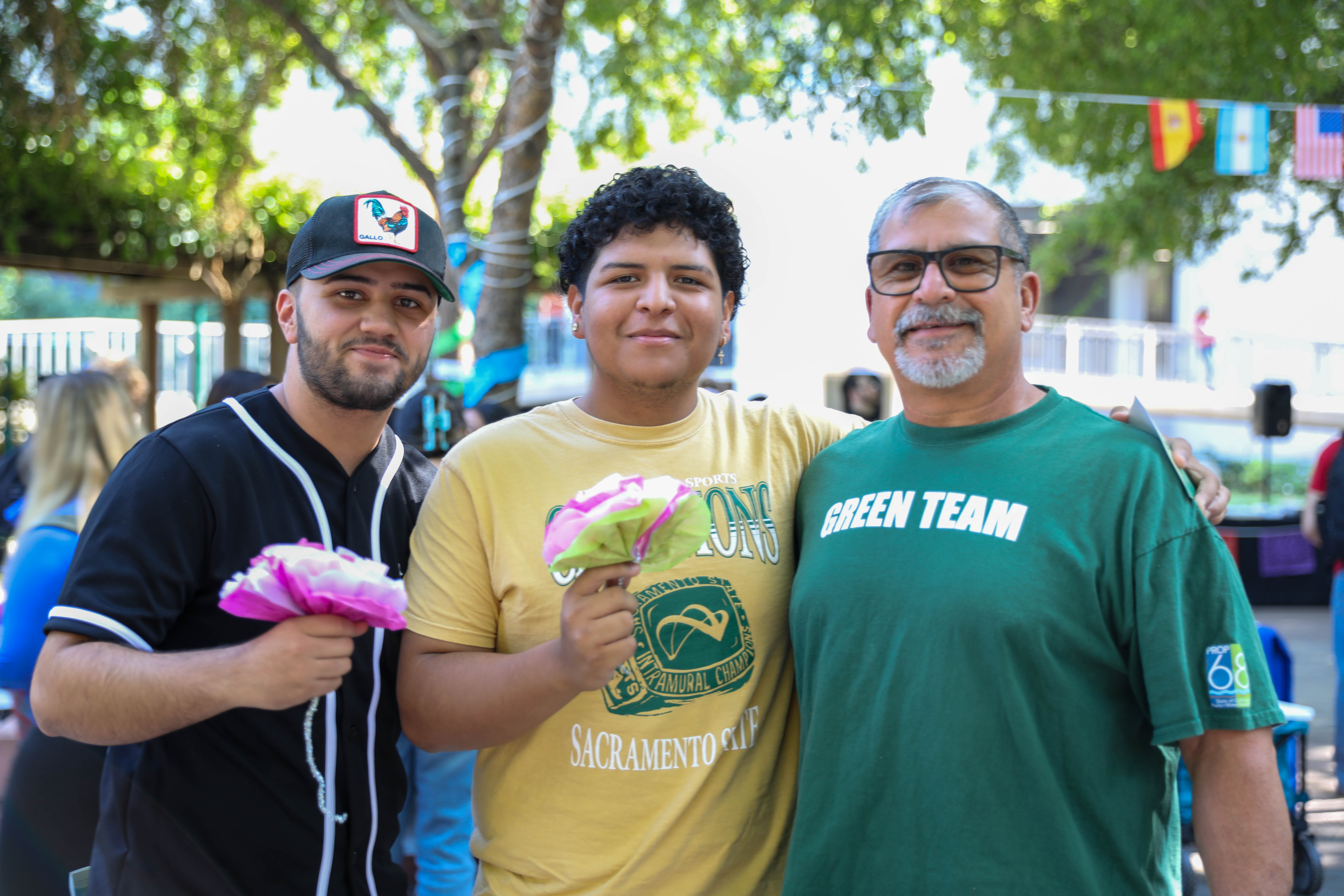 three students hold flowers and pose for the camera at the 2024 hispanic heritage month celebration