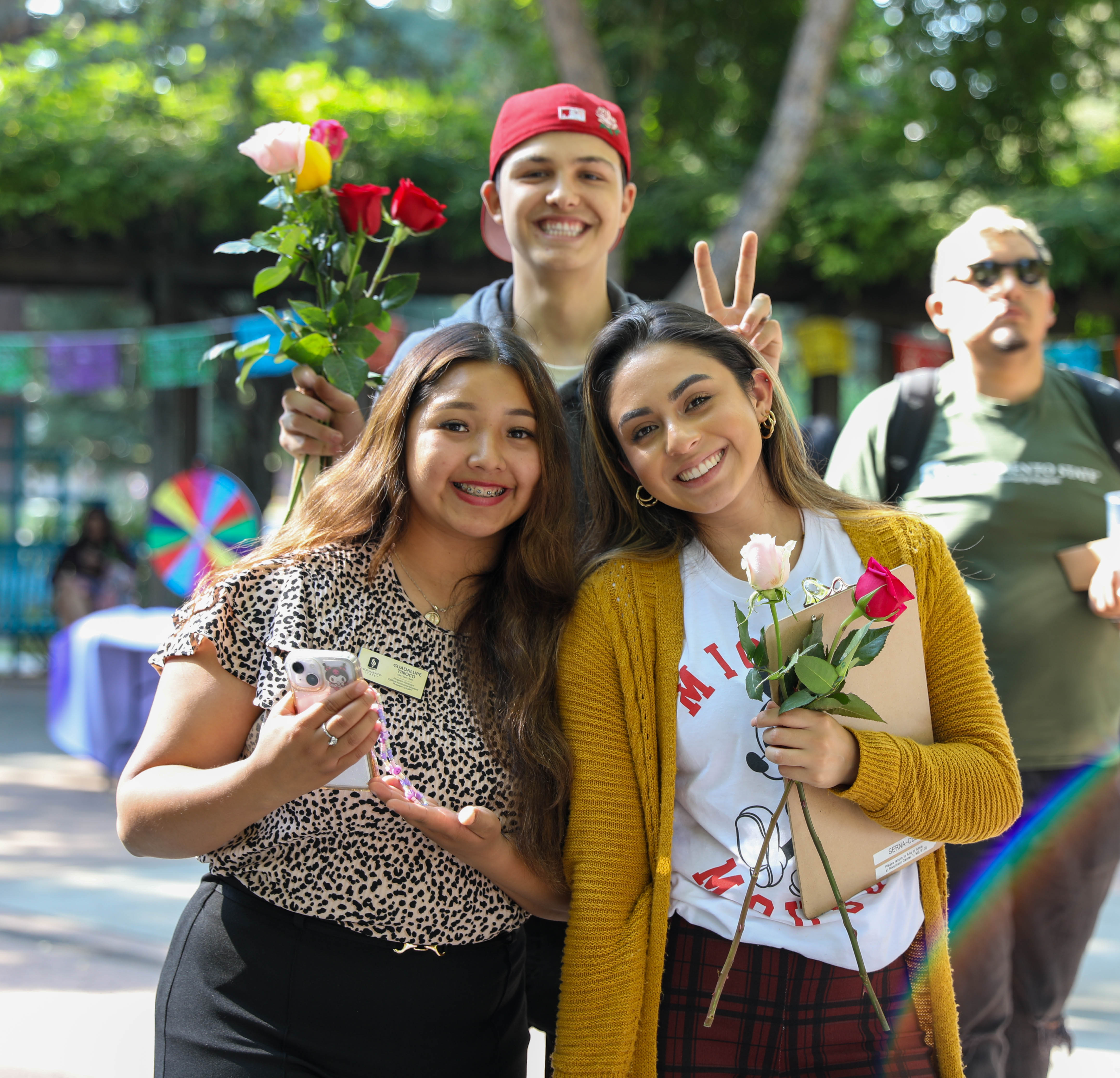 three students holding flowers and posing at the 2024 Sac State hispanic heritage month celebration