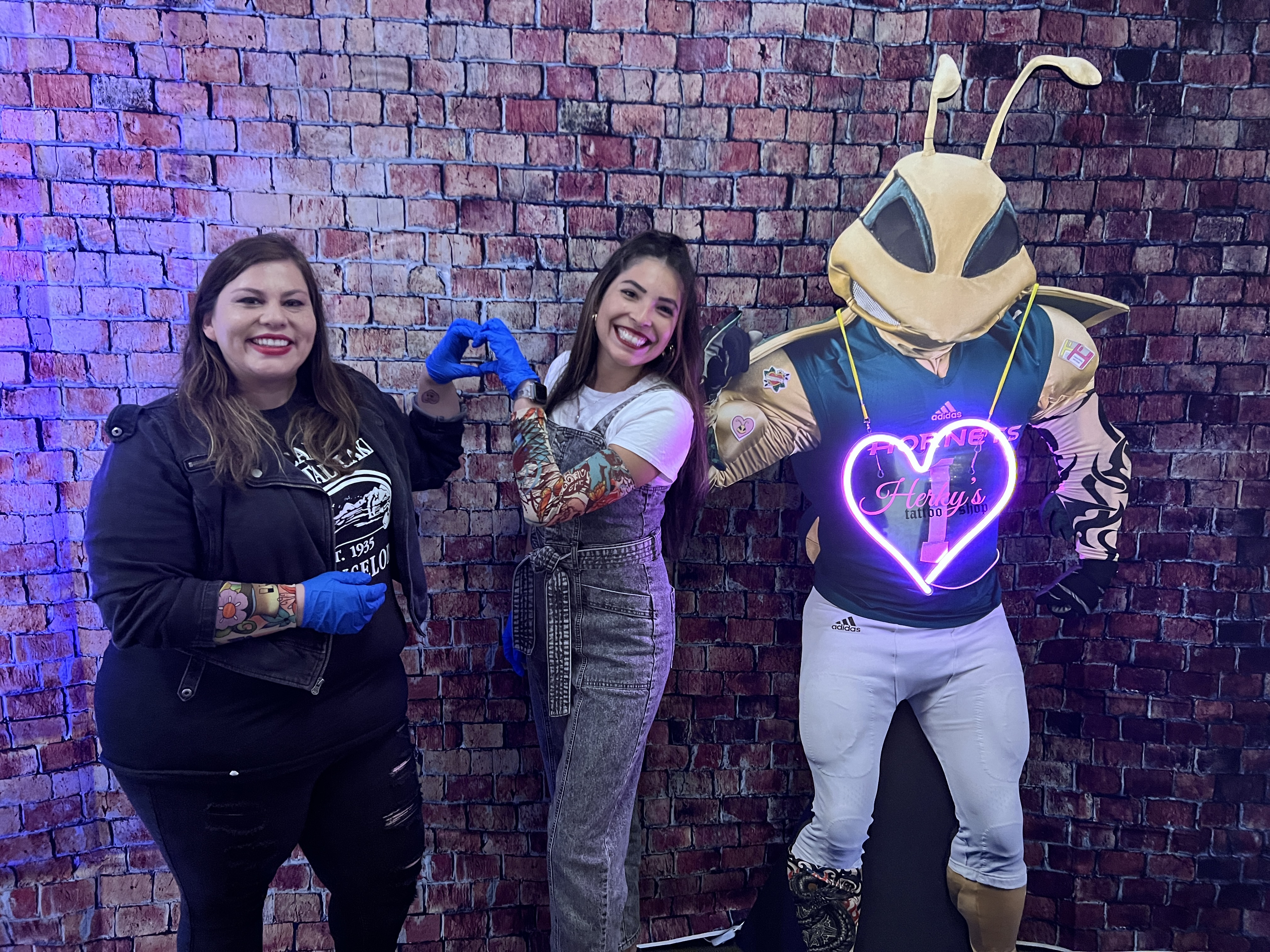 Staff and Herky the Hornet posing in their tattoo shop